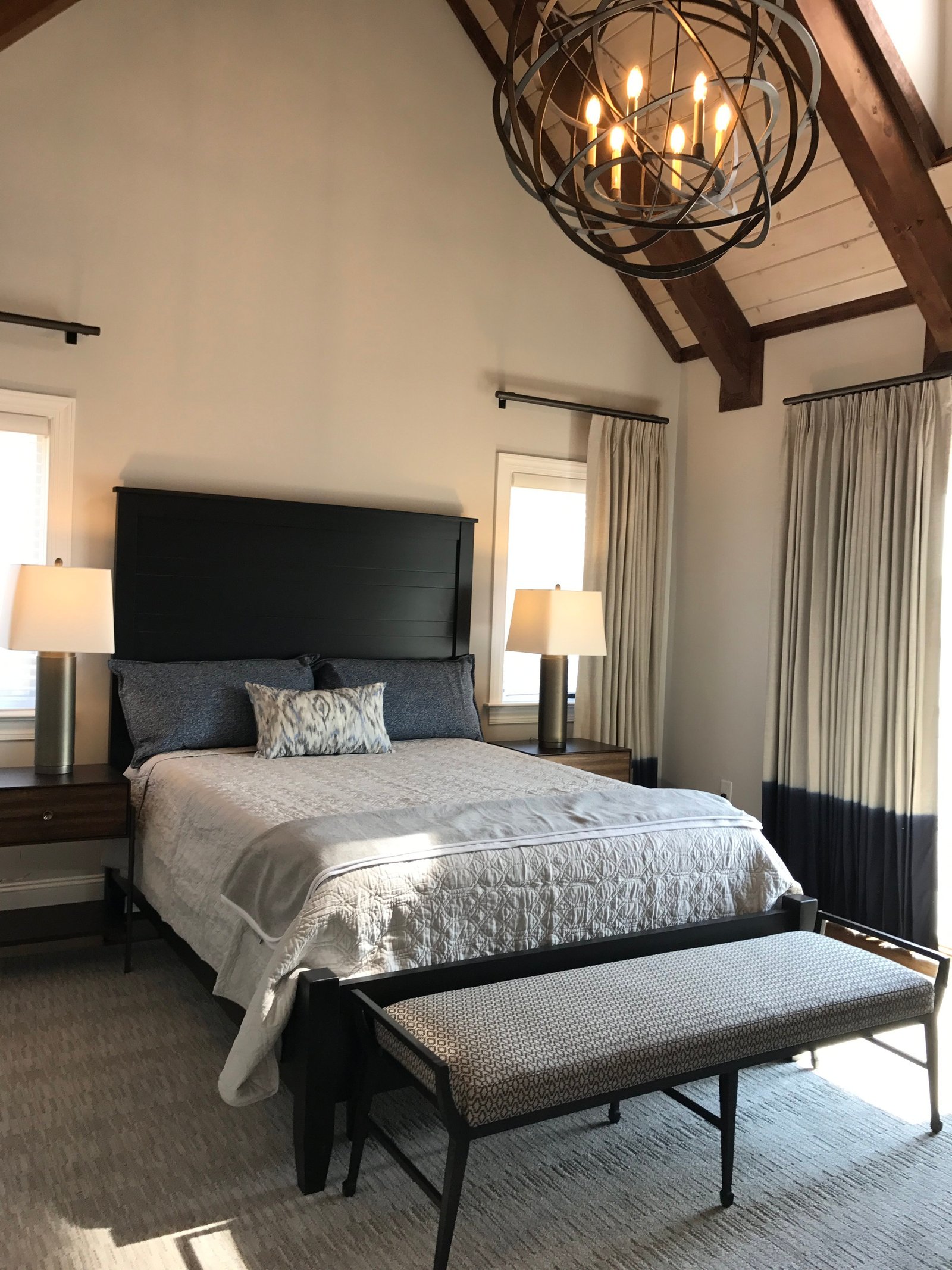 Bedroom beneath a timber-beamed vaulted ceiling with an orb chandelier