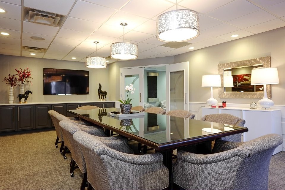 Long view of the conference room with white table lamps, a silver mirror and a charcoal credenza