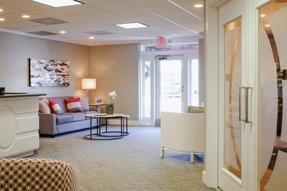 Reception seating area with a gray sofa, red and white pillows and a round nesting coffee table