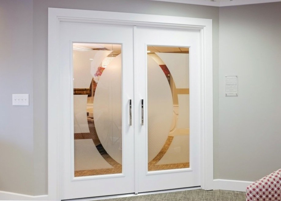 White double doors with frosted glass panels etched with a sweeping oval motif