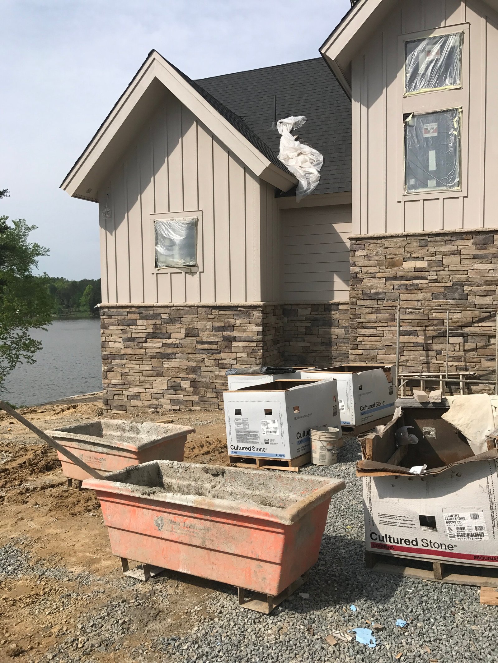 New home under construction with board-and-batten siding and stacked stone