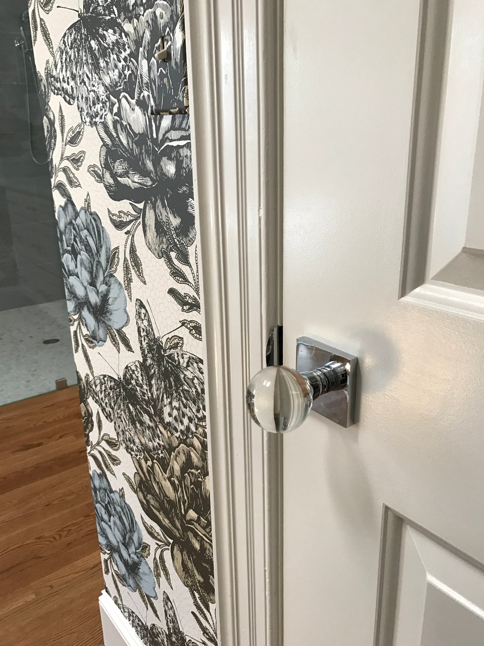 Lucite door knob on a white door beside blue-and-white botanical wallcovering