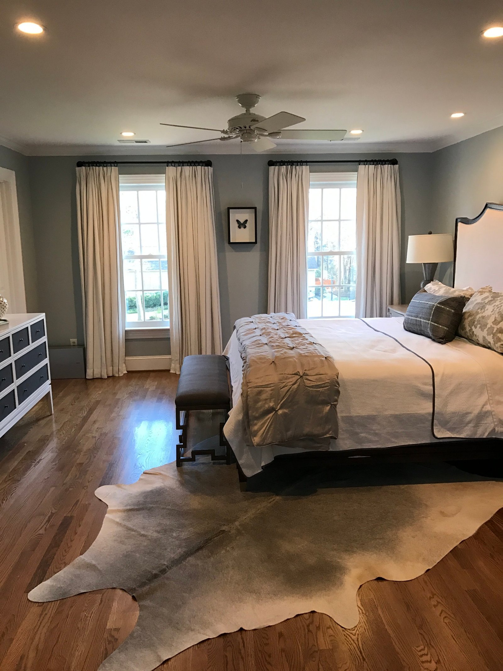 Irving Park primary bedroom with soft gray walls, an upholstered headboard and a hide rug