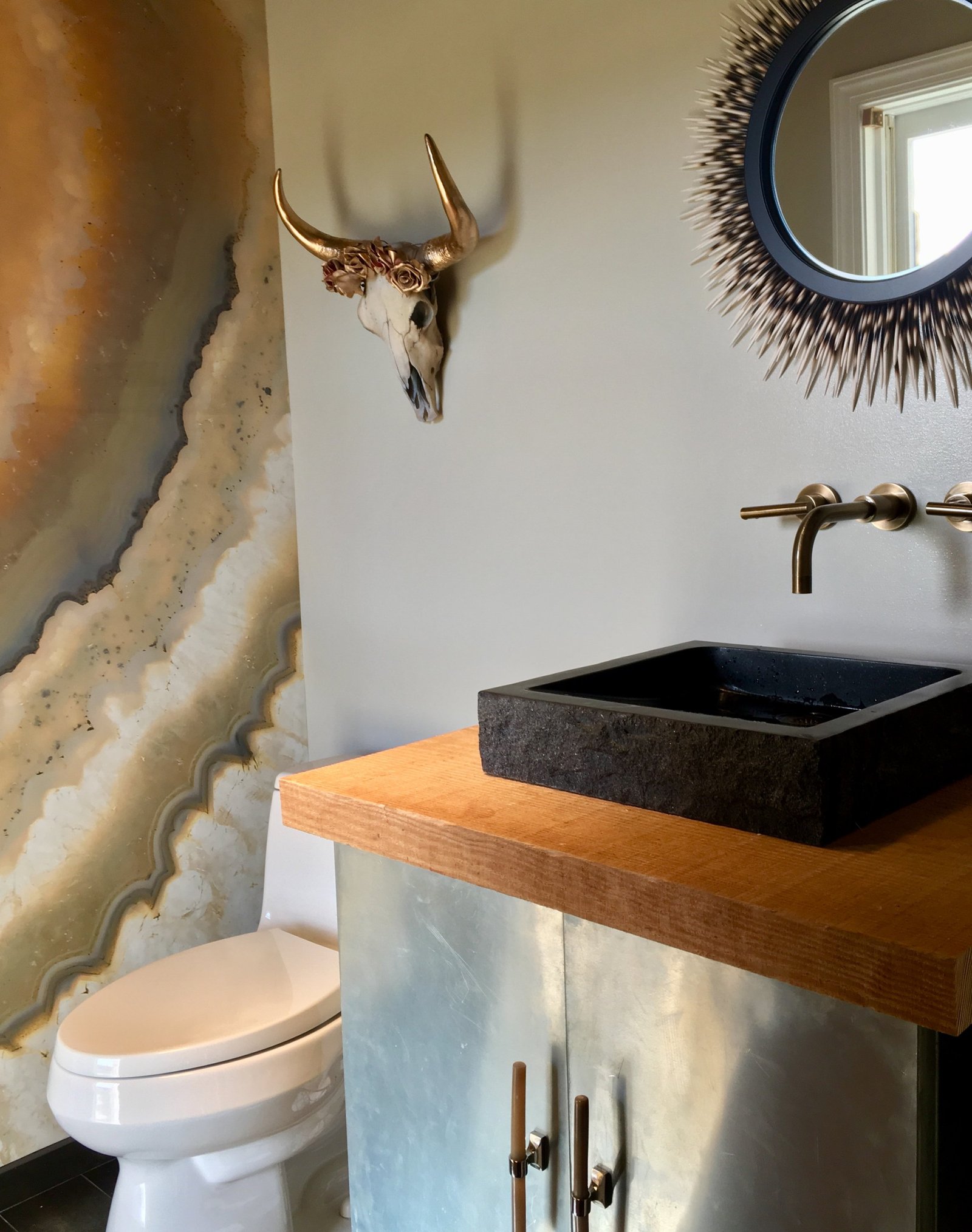 Powder room with an agate-inspired mural, stone vessel sink and walnut counter