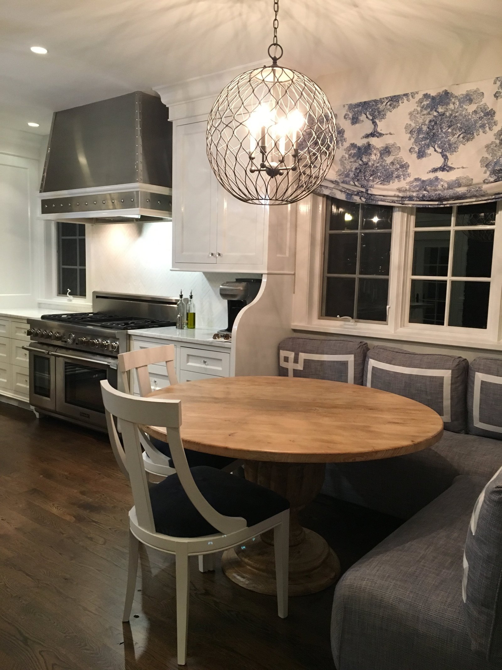 Rye, New York kitchen with a round breakfast table, a wire globe pendant and a stainless range hood