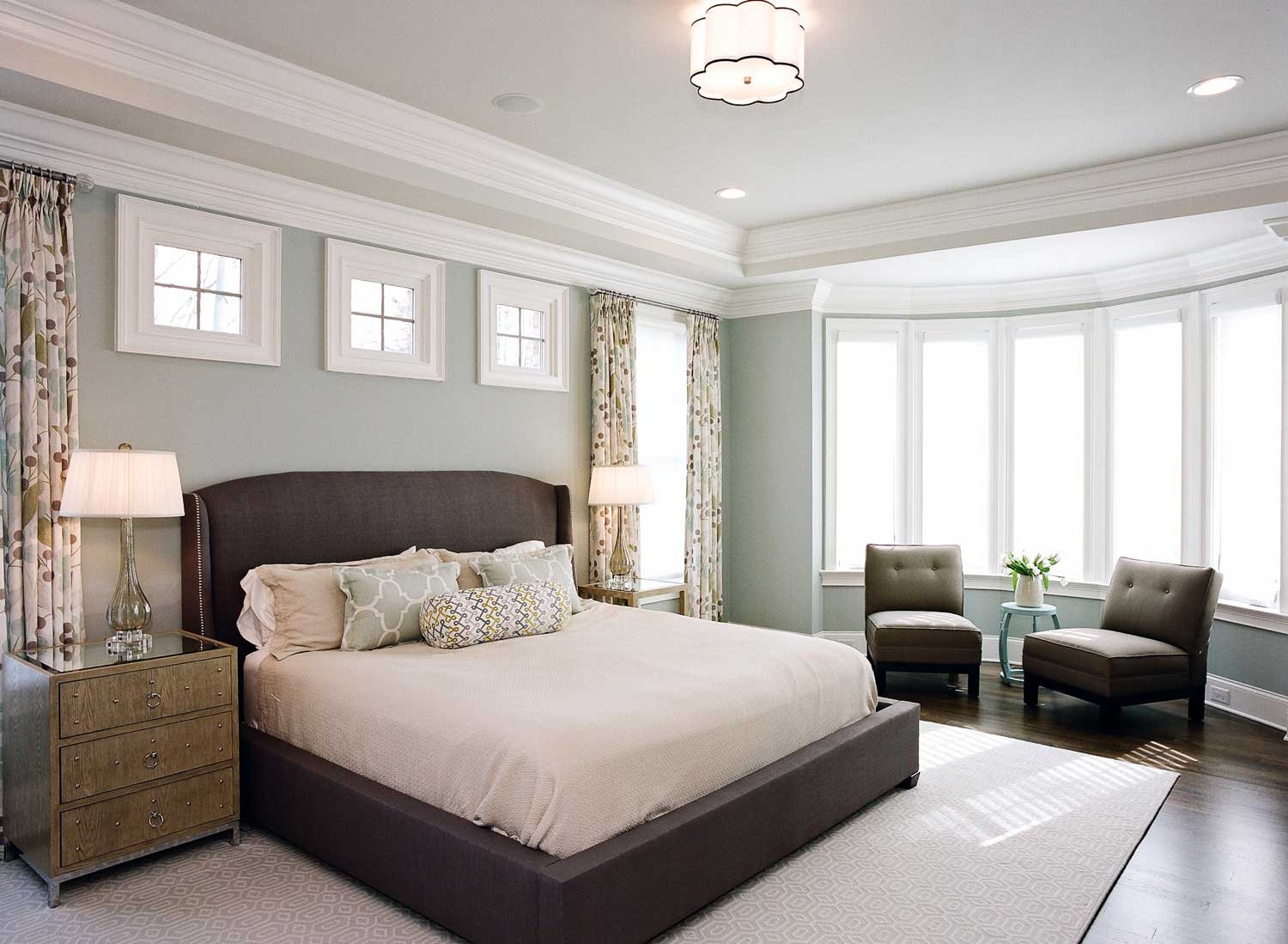Primary bedroom with a dark upholstered bed, a bay window sitting area and soft sage walls