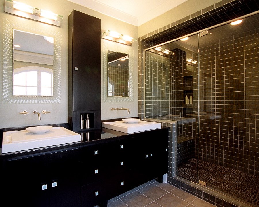 Bath with an espresso double vanity, vessel sinks, framed mirrors and a glass-enclosed tiled shower